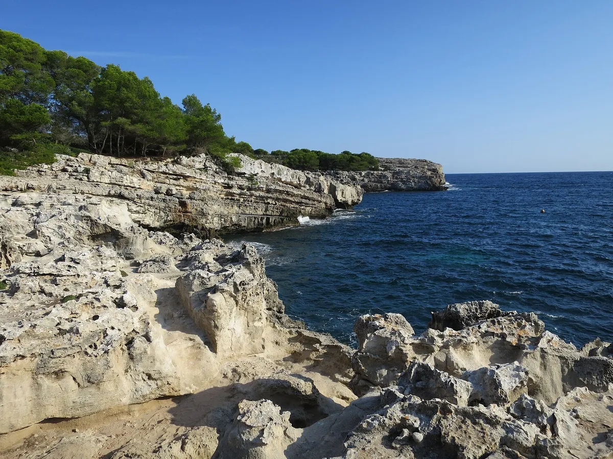 Rocky shoreline and clear water at Cala en Turqueta in Menorca in early-season light, before the July crowds arrive