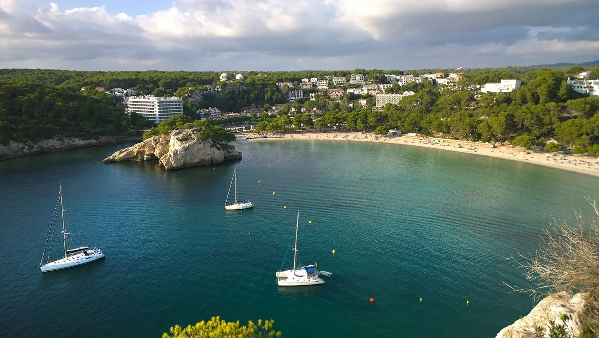 Sailing boats anchored in the turquoise bay of Cala Galdana in Menorca on a calm summer morning