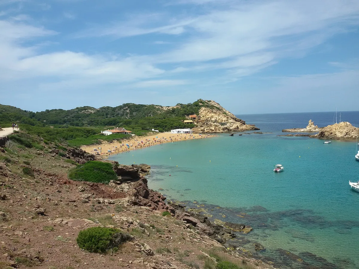 The red-gold sand of Cala Pregonda on Menorca's north coast, a marine reserve cove reached by boat rather than by road