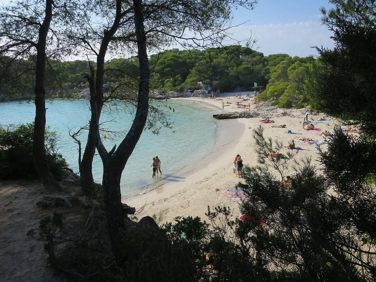 Shallow white-sand bay at Cala en Turqueta in Menorca where family boat trips anchor for swim stops with children