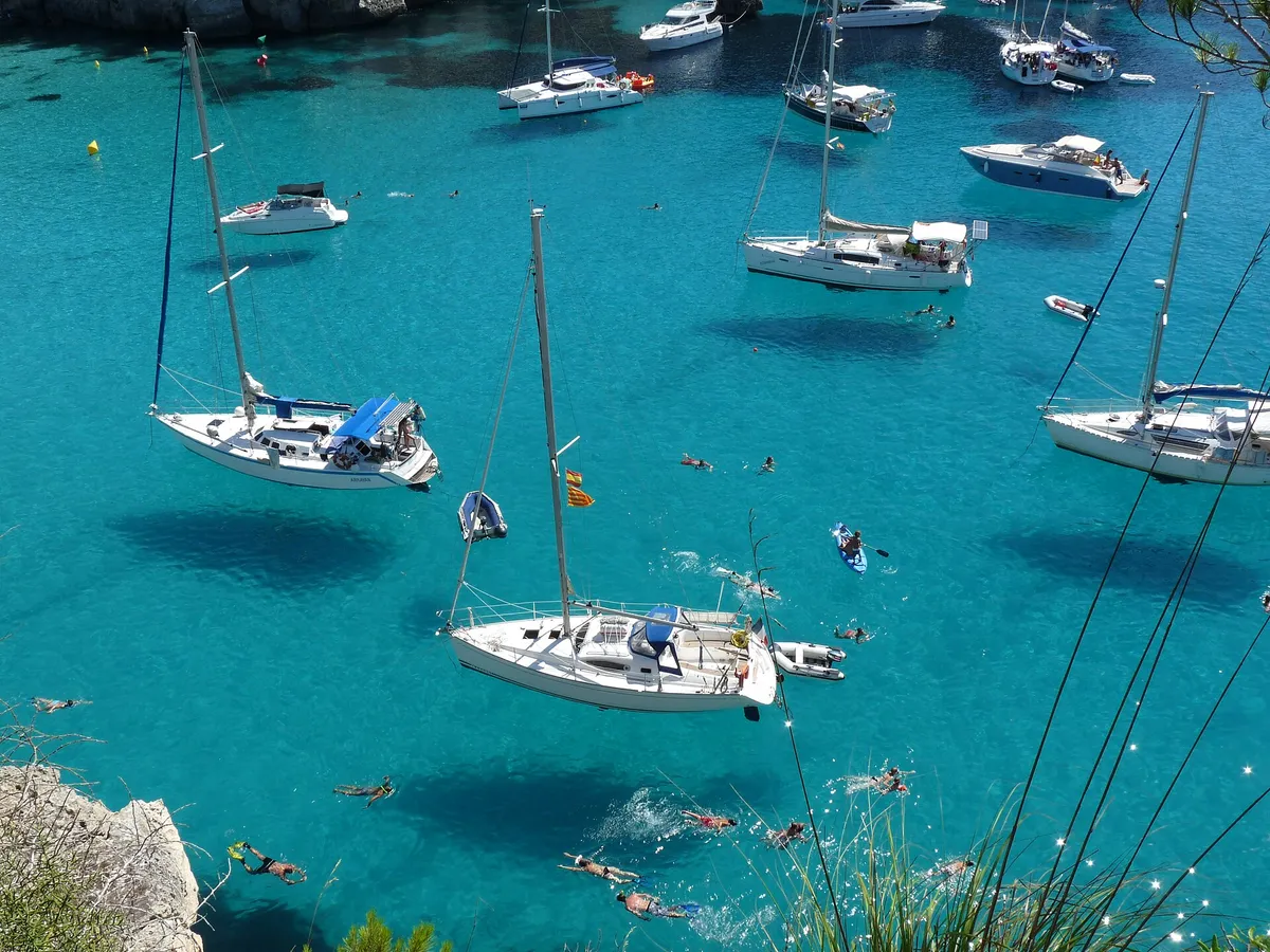 Turquoise swim-stop cove at Cala Macarella in Menorca where boat trips moor and swimmers go in already wearing swimwear