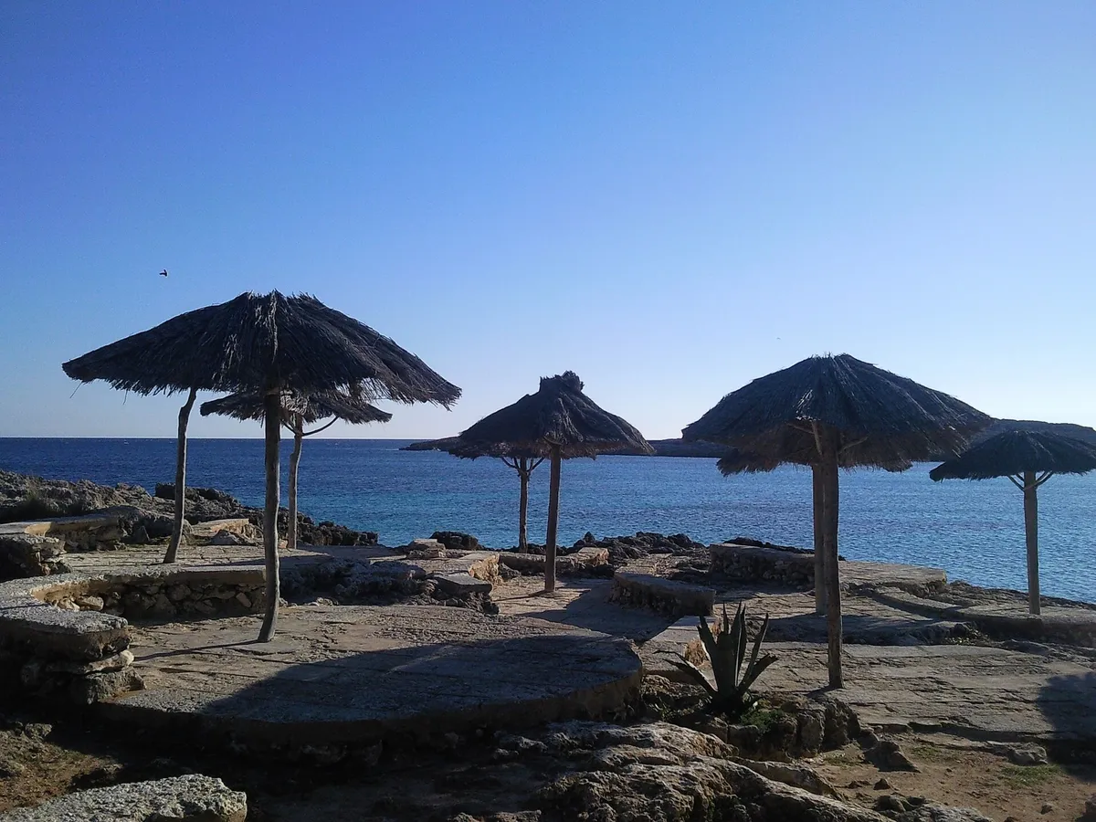 Parasols lined on Playa Binibeca in Menorca, the shade that swim-stop coves visited on a boat trip do not have