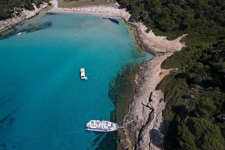 Blue and white boat leaving Cala Galdana beach in Menorca for a half-day south coast boat tour past the island's coves
